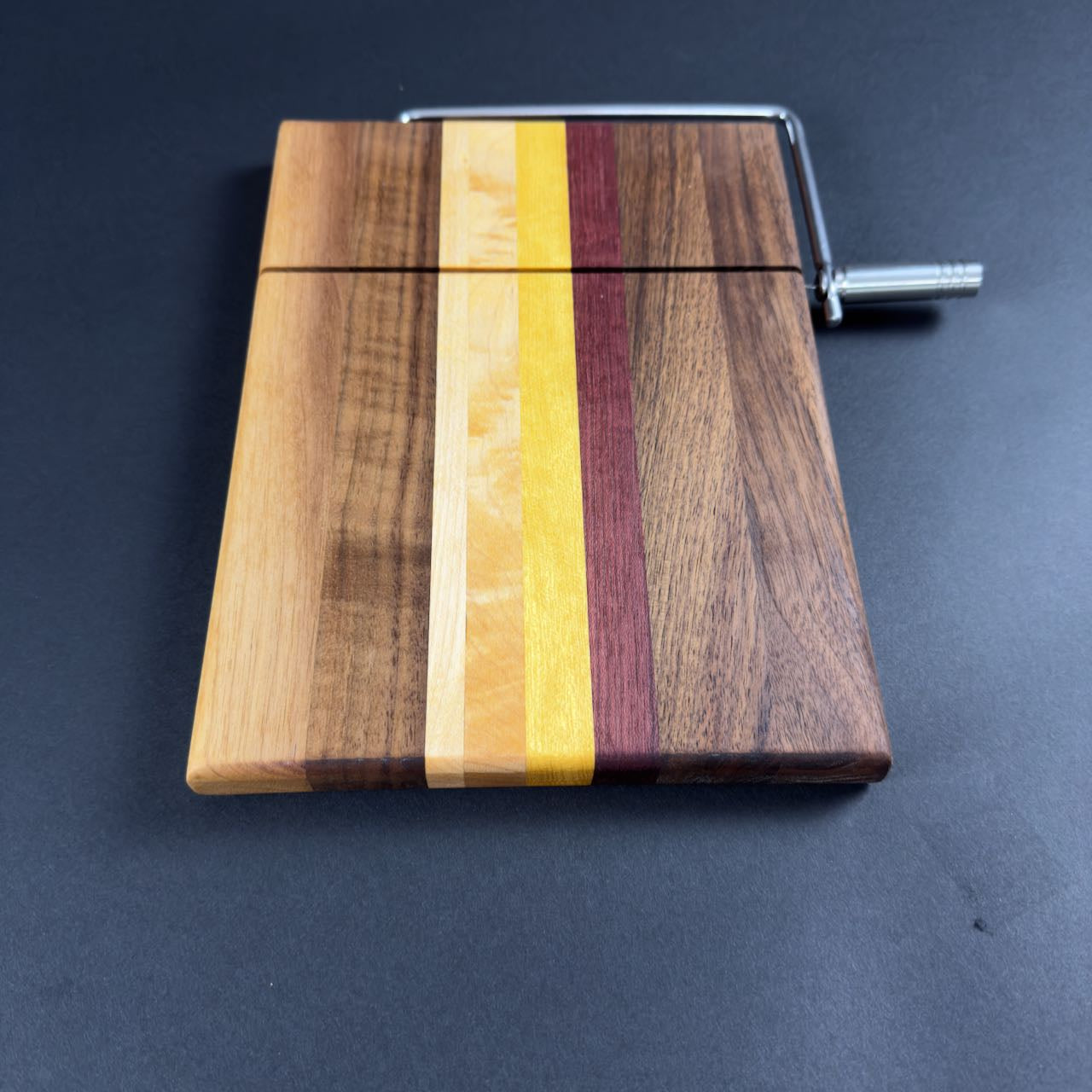 Stunning multicolored solid natural hardwood cheese slicing board, end view, measures 8 x 10.