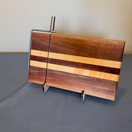 Cheese cutting board shown on its side in a rack. Chrome finish cutting handle and arm. Colorful linear pattern of walnut and maple. Measure a generous 8 x 13. Extra cutting wires included. Please contact me for additional assistance.