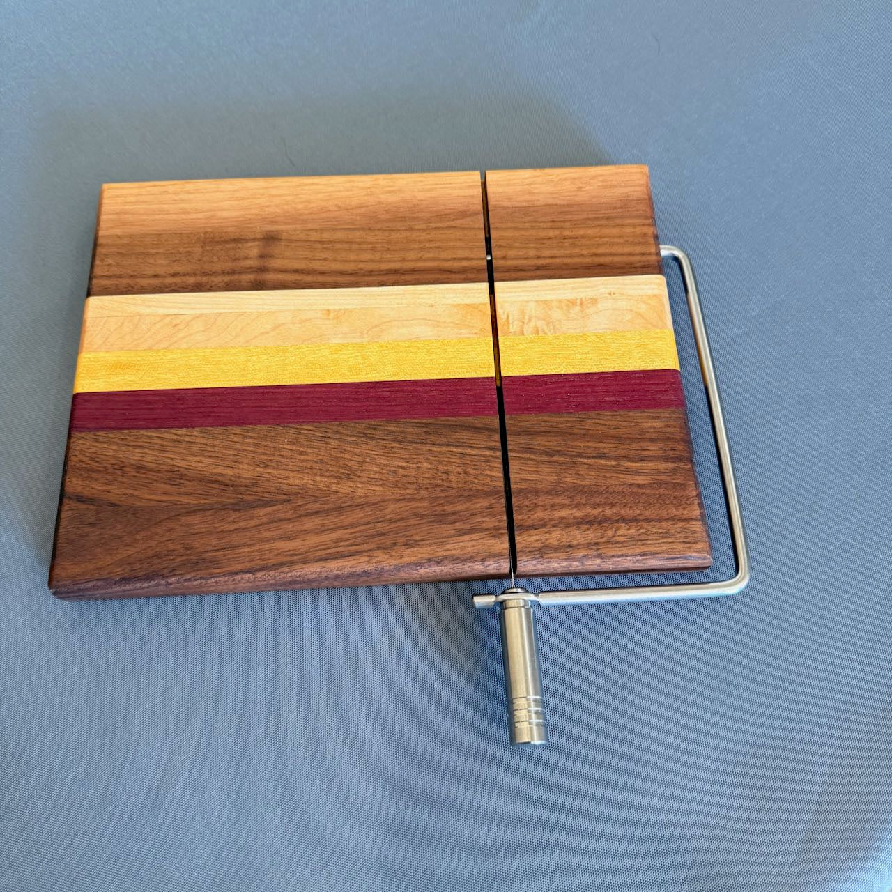 Stunning multicolored solid natural hardwood cheese slicing board, side view, measures 8 x 10.
