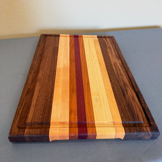 Beautiful solid hardwood cutting board with juice groove and finger holds for easy lifting. Made from walnut, cherry, maple and purple heart. 12 x 18 1.25 end view.