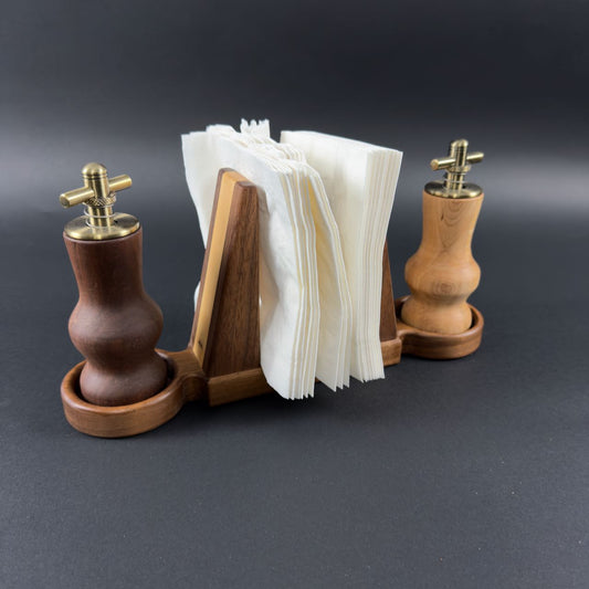 Hand crafted wooden salt and pepper shakers on each end of a  napkin holder on a dark background