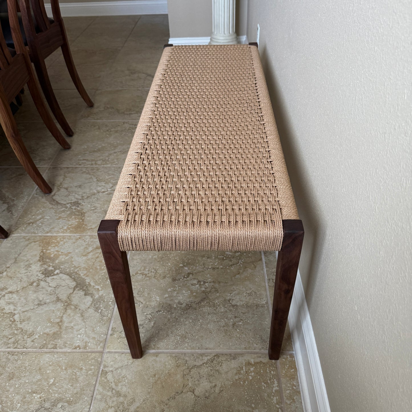 Long view from the end of tapered legs on a woven seating area bench.
