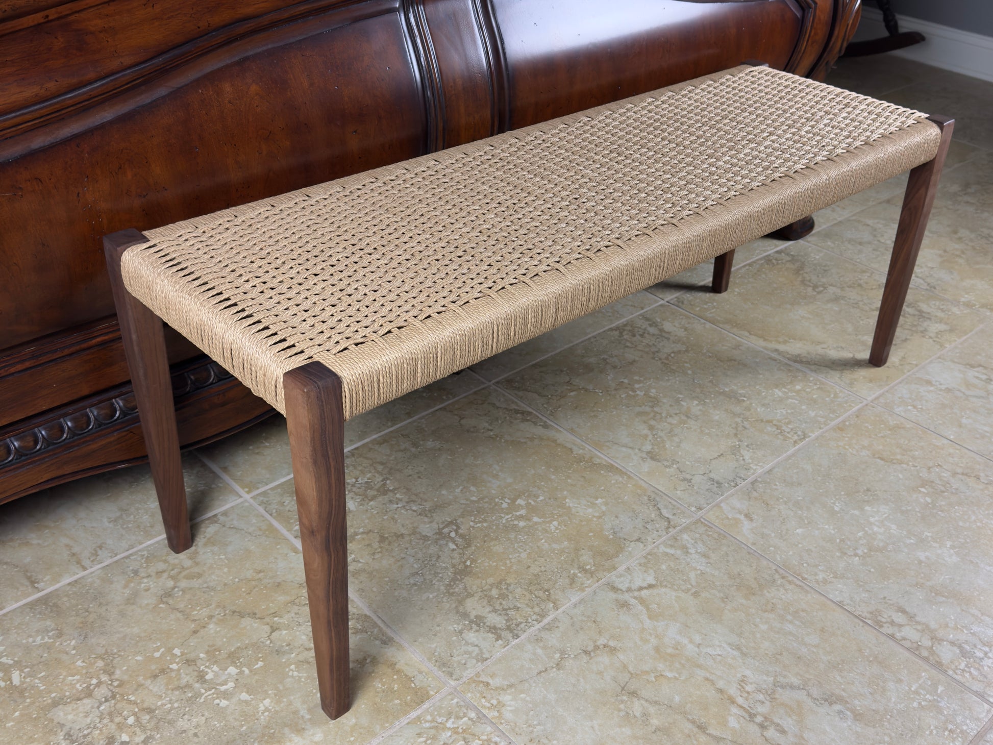 Solid walnut tapered legs on a rectangular bench with a Danish paper cord weave seating area at the foot of an ornate bed footboard. 47 x 16 x 18 inches tall. Please reach out for additional help.