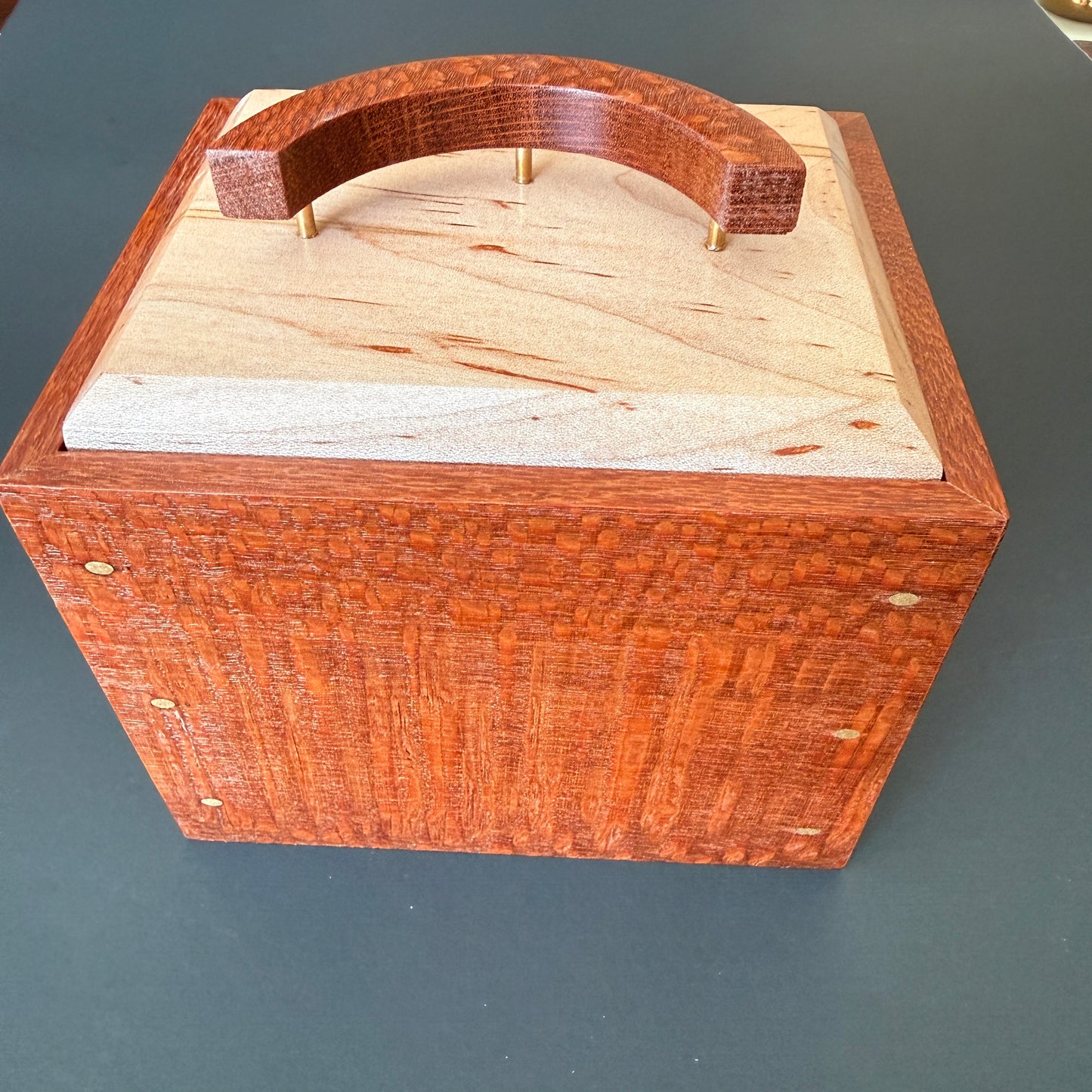 Beautifully crafted keepsake box.  Side view. The body is make of leopard wood with an ambrosia maple top. The handle is a crescent moon shape standing on three thin brass posts.  Small brass accents adorn the corners. It measures 6 x5 and 6 1/2 inches tall. For additional help please reach out to me.